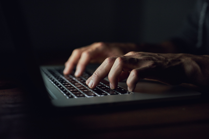 Unidentifiable man using a laptop late at night